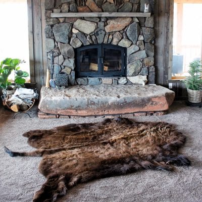 buffalo hide being used as a rug in front of a fireplace